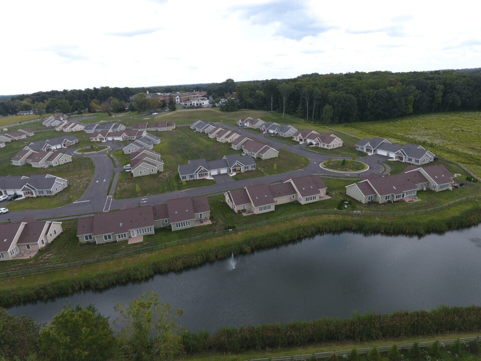 Aerial view of a suburban residential neighborhood with a pond in the foreground.