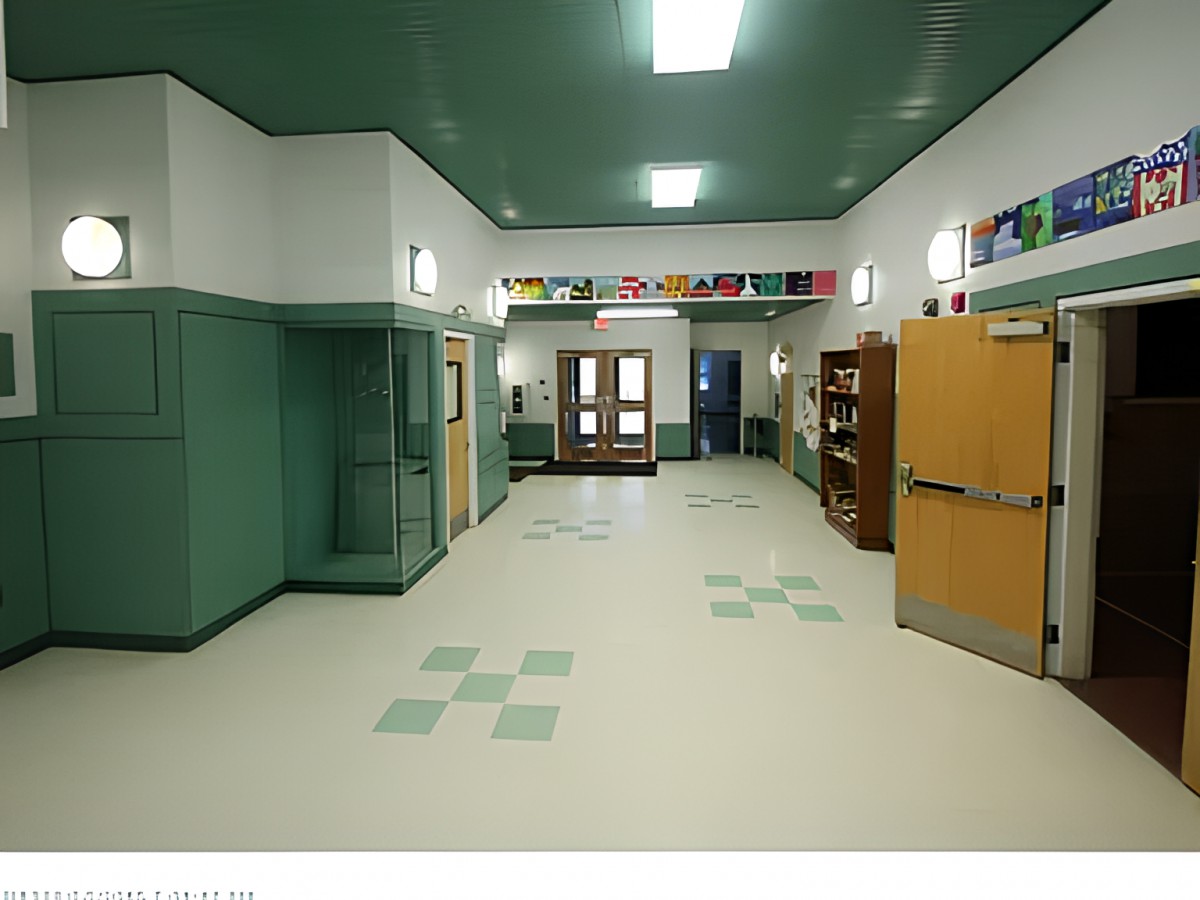 An empty school hallway with green accents and decorated doors.