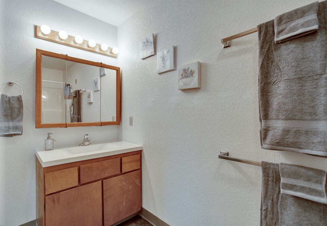 A clean and simple bathroom with a wooden cabinet, mirror, and towel rack.