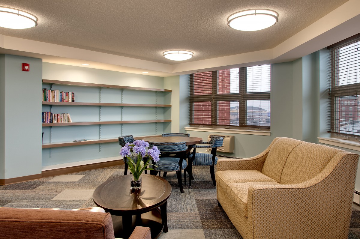 A cozy living room with a sofa, table, and bookshelf adorned with decorative items.
