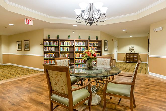 A cozy library with a round table and chairs, surrounded by bookshelves.
