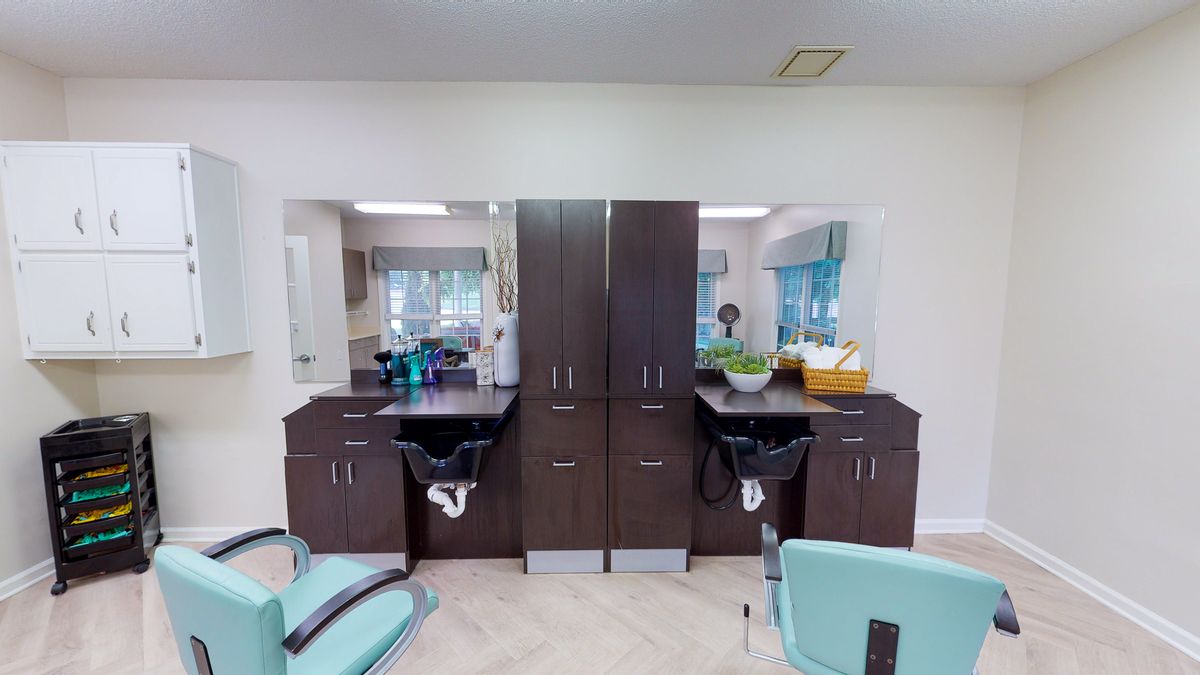 Interior of a hair salon featuring chairs, mirrors, and cabinets.