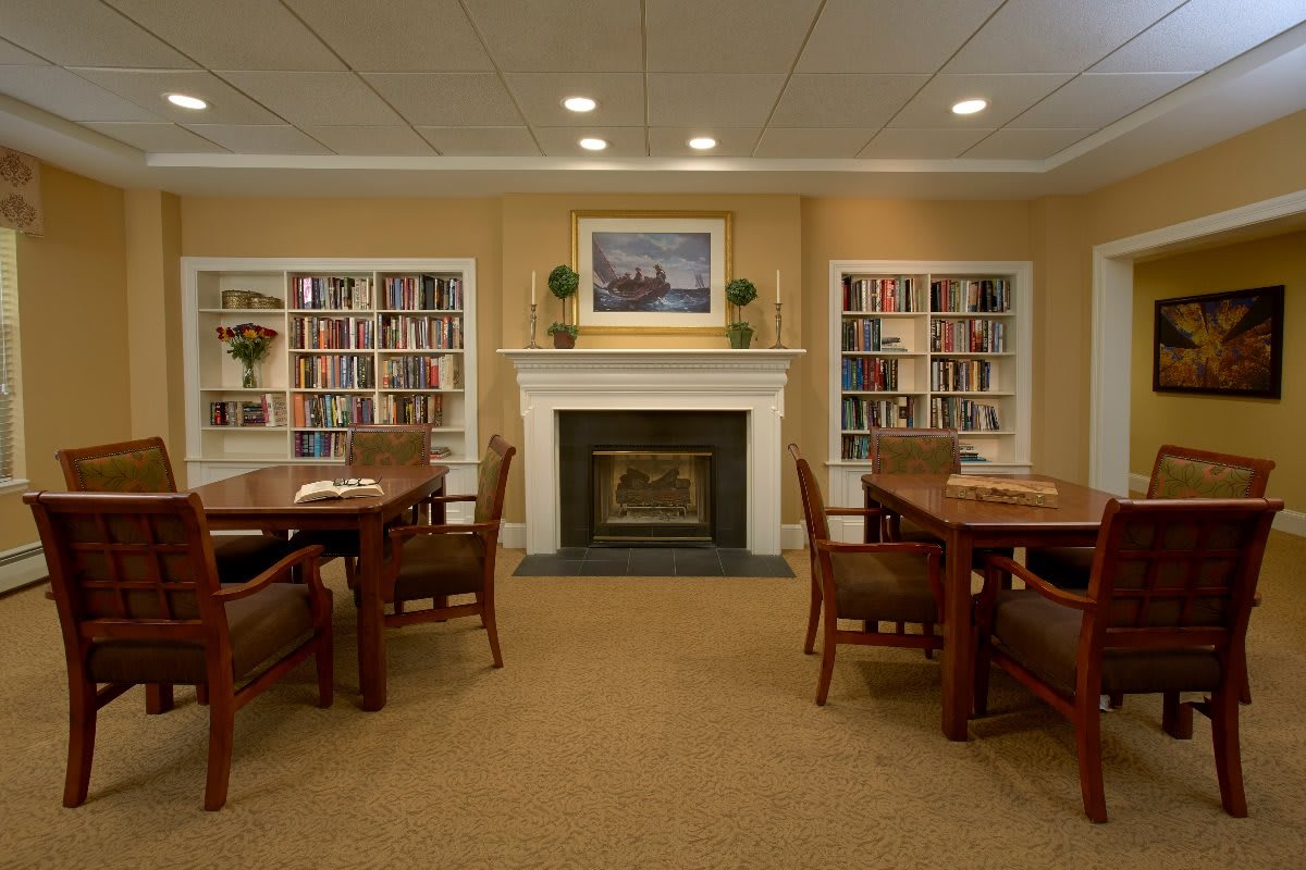 A cozy library setting with bookshelves, a fireplace, and seating area.