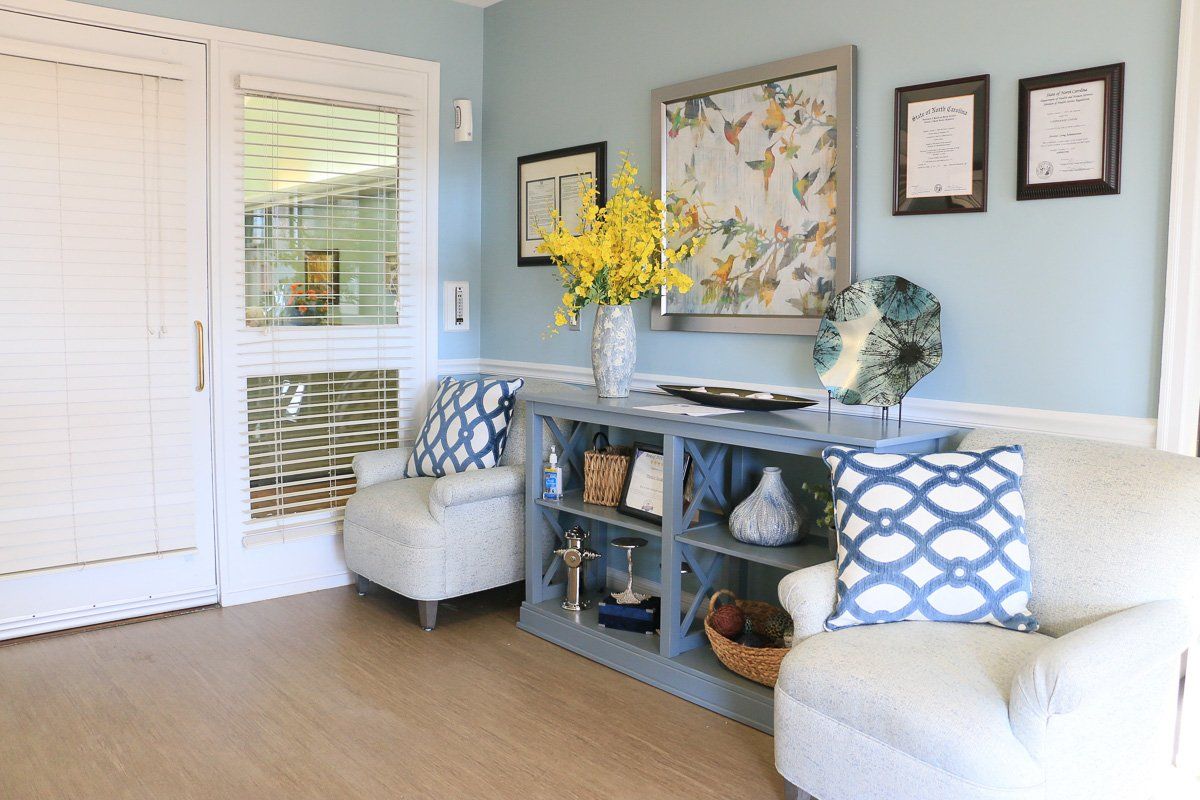 A cozy and modern living room with comfortable seating, decorative pillows, a stylish shelving unit, and vibrant floral arrangements.