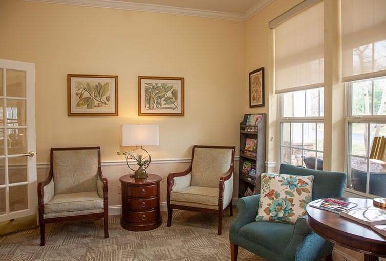 Cozy living room with armchairs, a lamp on a side table, and framed artwork.