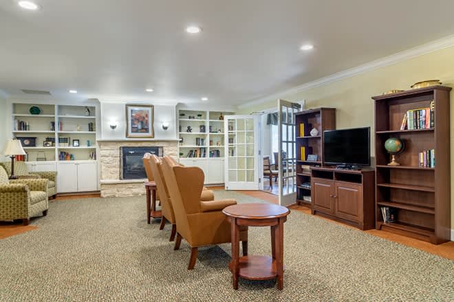 A cozy living room featuring comfortable armchairs, a fireplace, and a television setup with surrounding shelves.