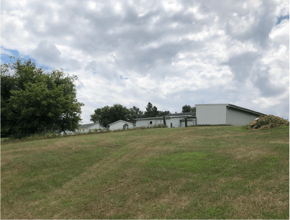 A grassy slope leading up to a group of buildings under a cloudy sky.
