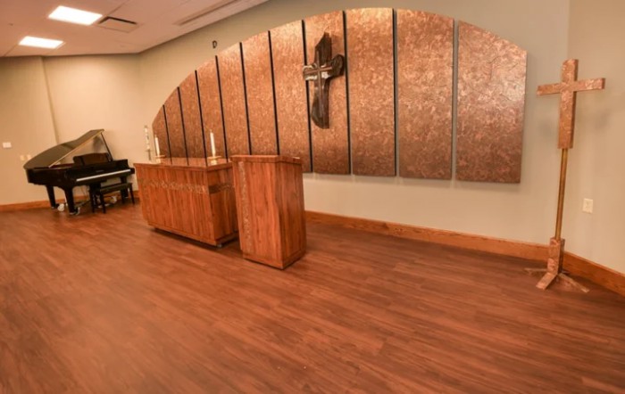 A modern chapel interior featuring wooden furniture and a cross on the wall.