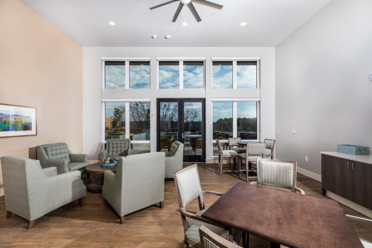 A modern living room featuring comfortable seating and large windows, illuminated by natural light.