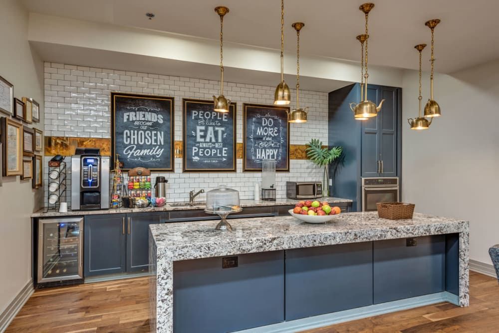A modern kitchen with a marble island, pendant lighting, and decorative wall signs.