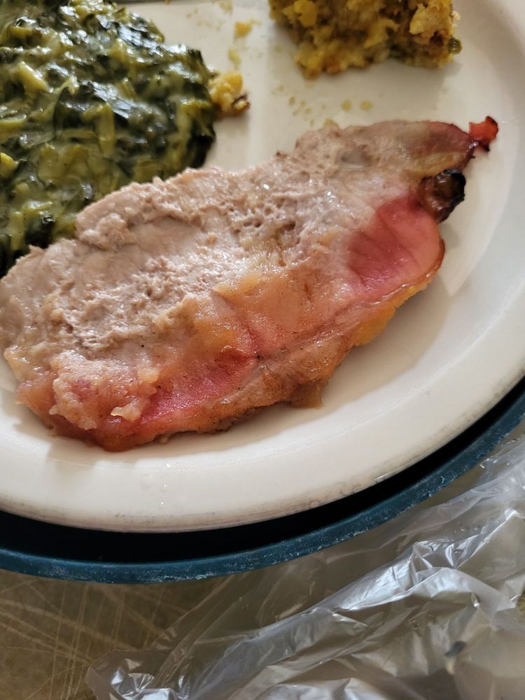 A serving of meat topped with a creamy sauce, accompanied by creamed spinach.