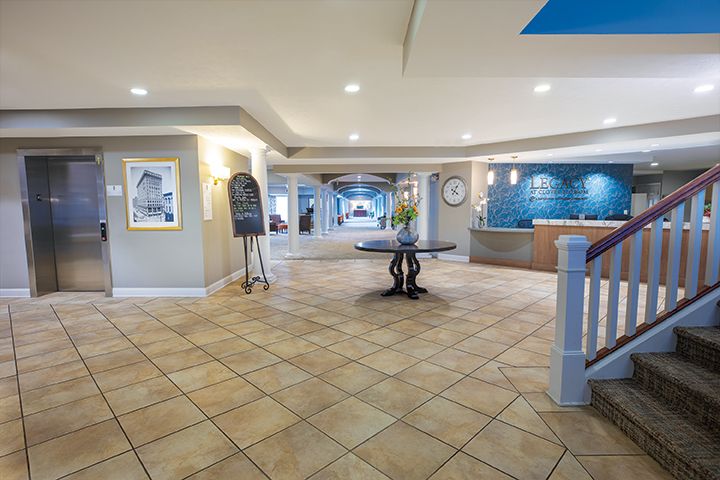 A spacious and well-lit hotel lobby with a central table and reception desk.