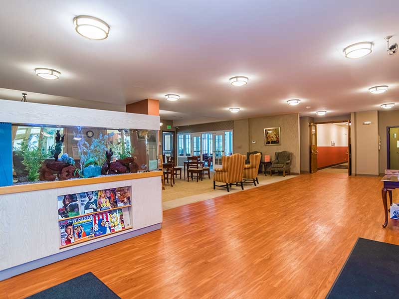 A welcoming lobby area with wooden flooring, comfortable seating, and an aquarium.