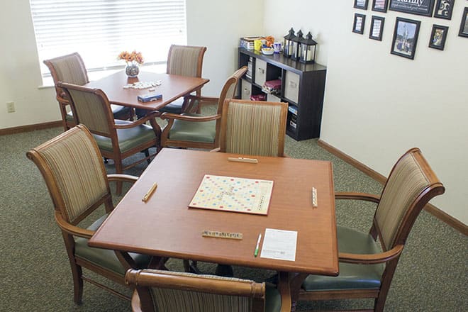 A cozy game room features tables with Scrabble boards and a coffee station.