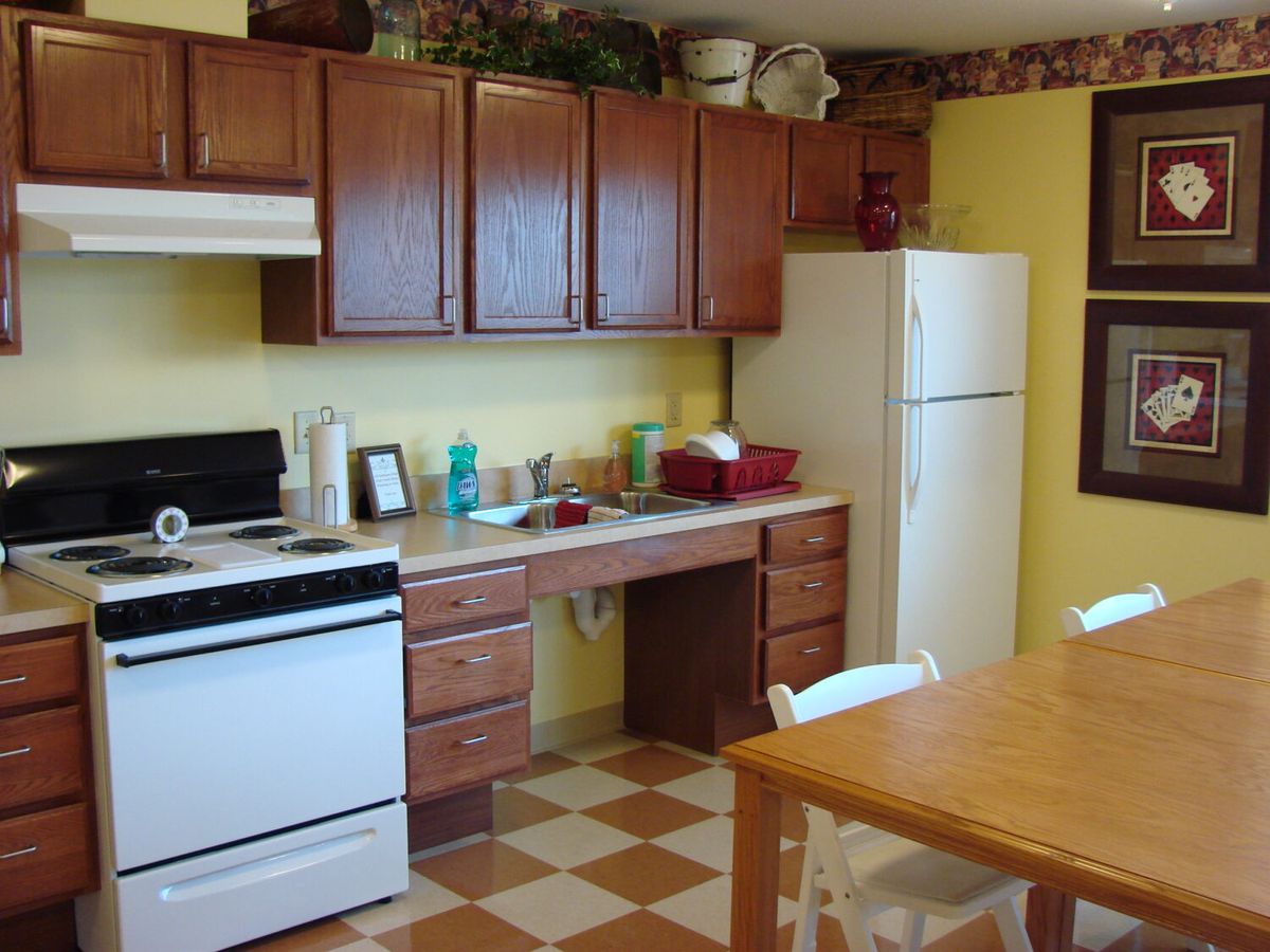 A cozy kitchen with wooden cabinets, a stove, refrigerator, and dining table.