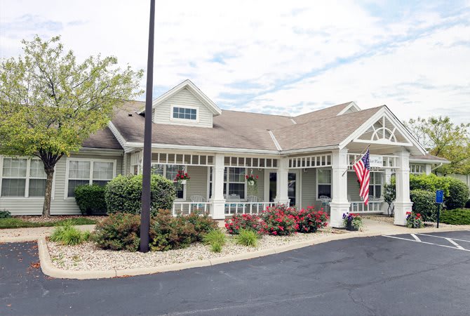 A residential building with an American flag in front, surrounded by landscaping and a driveway.
