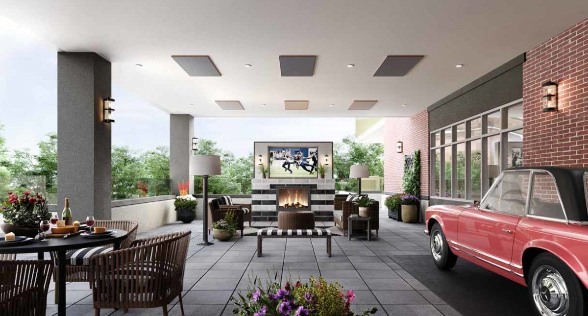 A modern outdoor patio with comfortable seating, a large fireplace, and a television for entertainment.