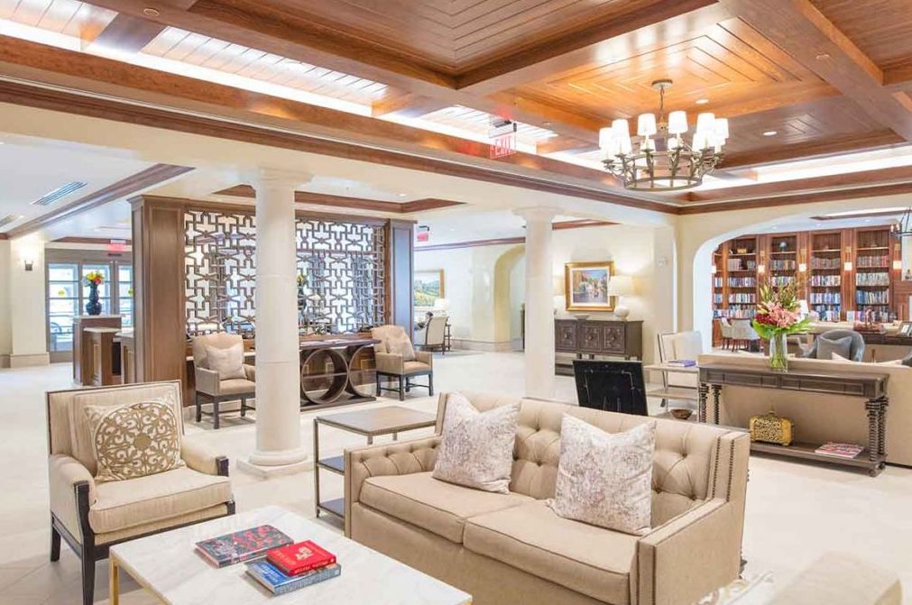 A luxurious and elegantly designed living room featuring plush sofas, a chandelier, and decorative columns.