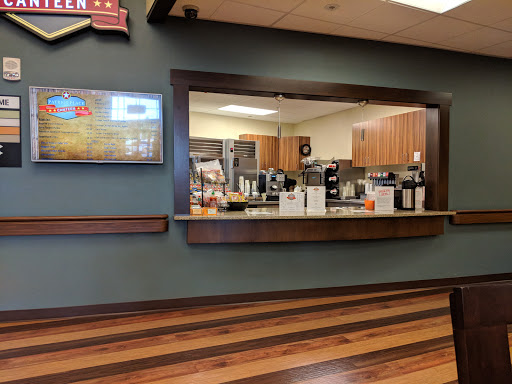 A cozy cafe interior showcasing a well-equipped kitchen with wooden flooring and modern decor.