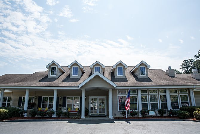 A charming building with a decorated porch and multiple dormer windows.
