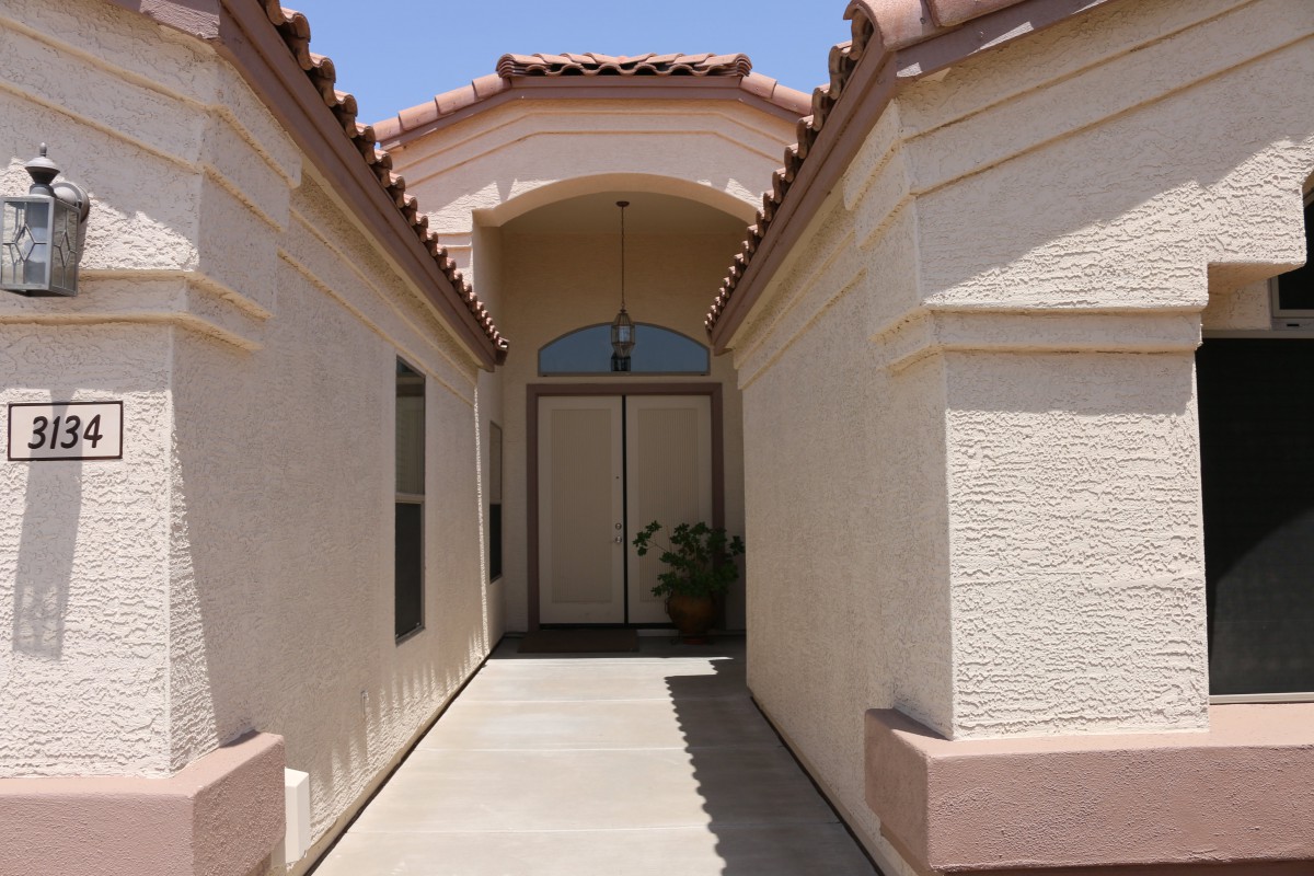A walkway leading to the entrance of a residential house with an arched roof.