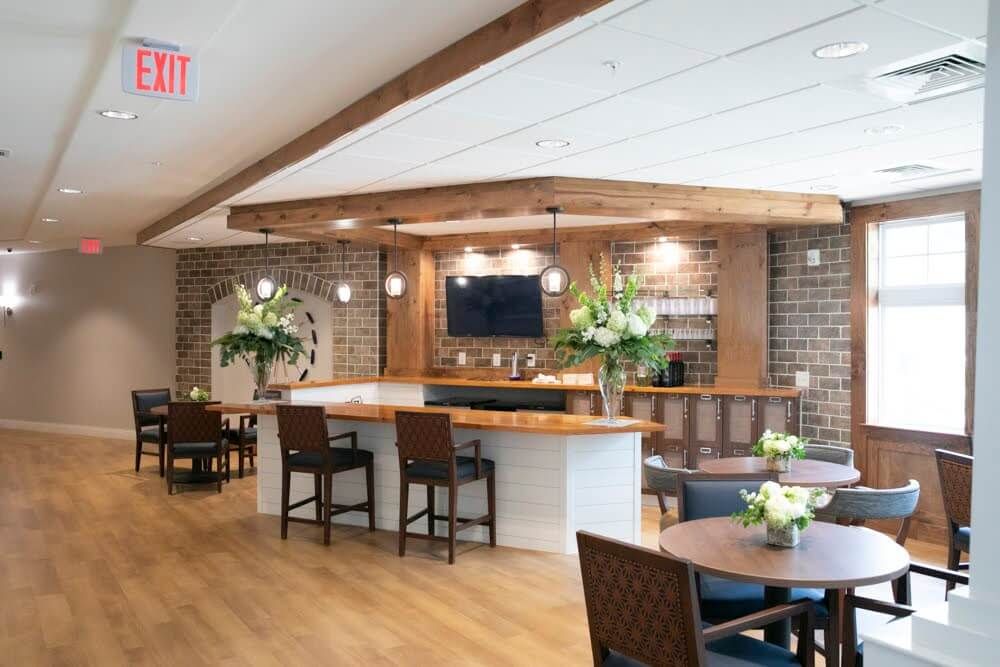 A modern bar and restaurant interior with wood and brick elements, featuring seating areas and a television.