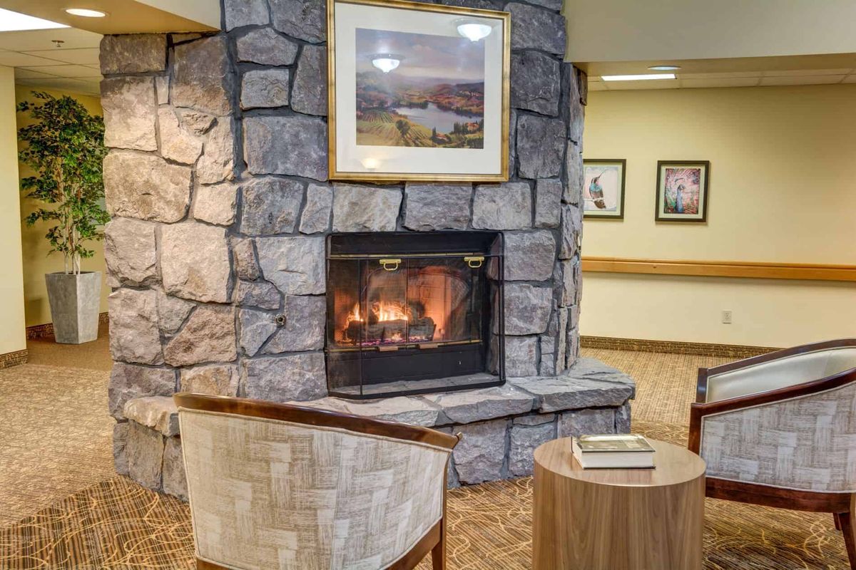 A cozy indoor seating area with a stone fireplace and artwork above it.