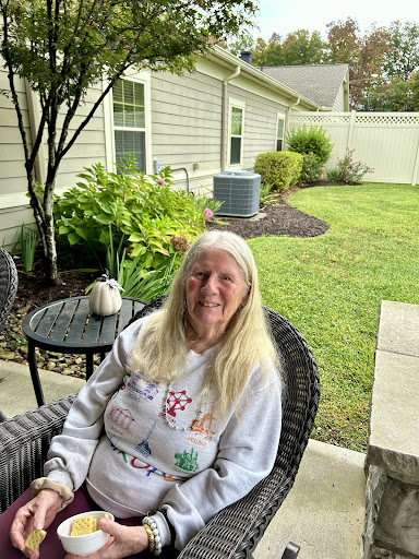 A woman enjoys a peaceful moment in her garden, surrounded by greenery.