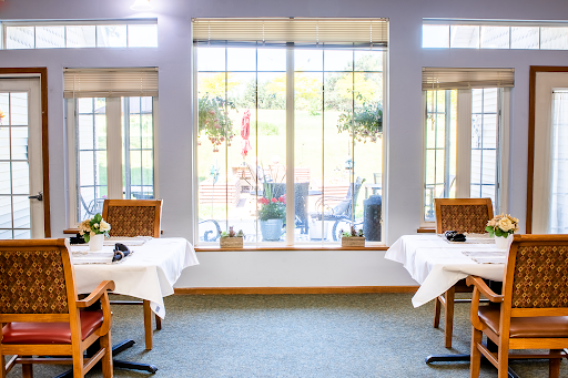 A cozy dining area with tables set for guests, featuring large windows that offer an inviting view of the outdoors.