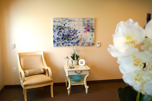 A cozy and stylish room featuring a comfortable chair, a decorative table with plants, and an abstract artwork on the wall.