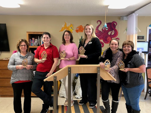 A group of women proudly holding their awards in a cheerful indoor environment.
