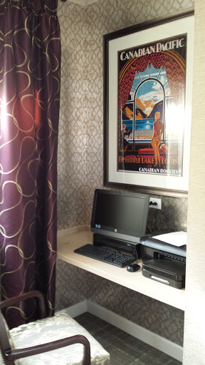 A cozy workspace featuring a computer, printer, and an artistic poster.