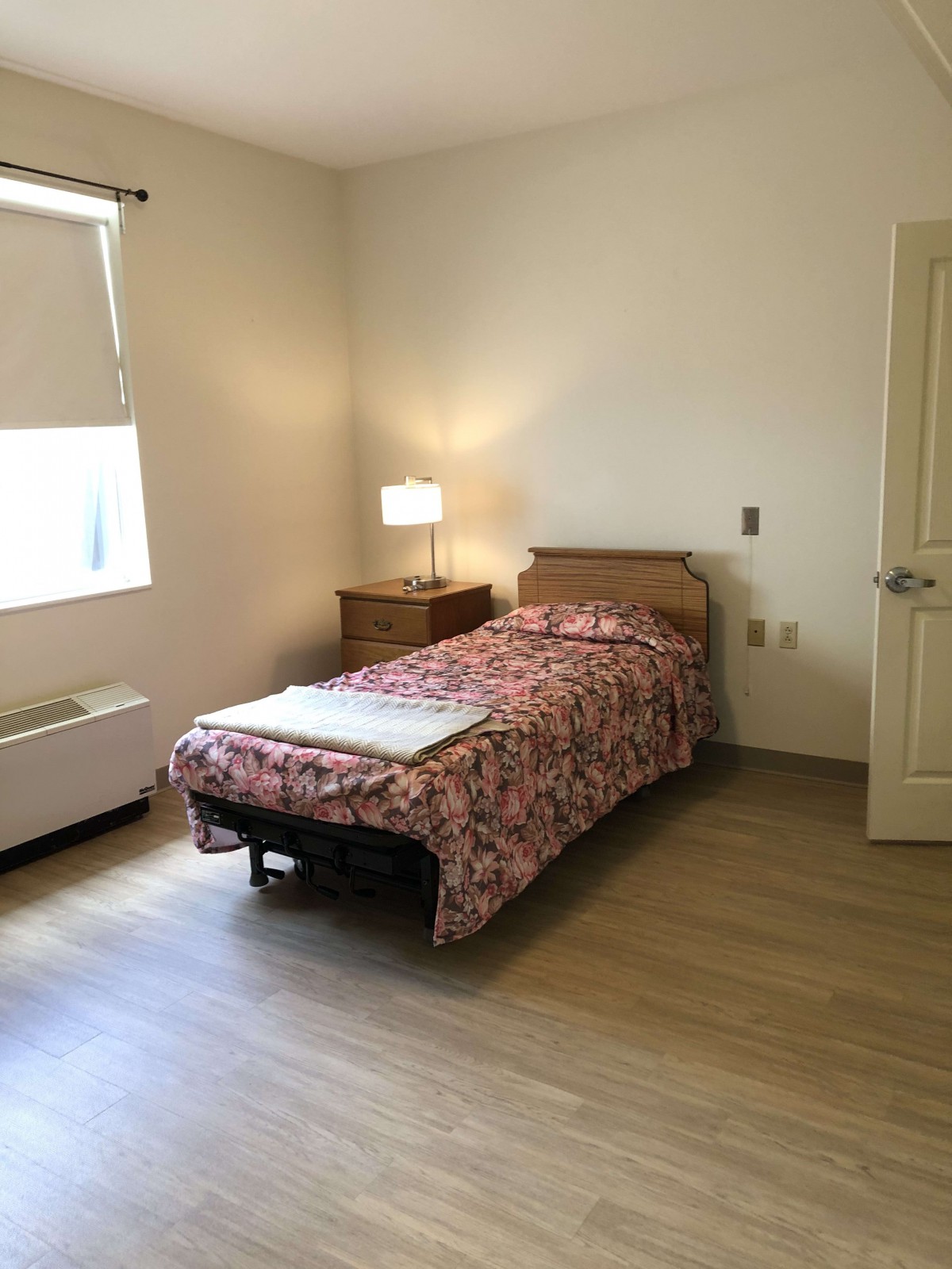 A minimalist bedroom with a single bed, nightstand, and lamp.