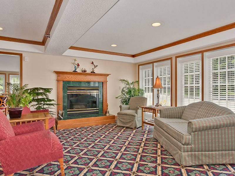 A cozy living room with a fireplace, armchairs, and large windows providing natural light.