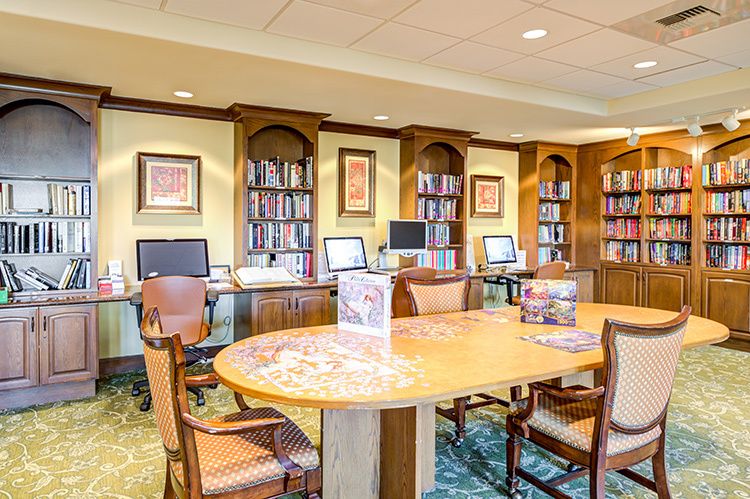 A cozy library space with wooden furniture, bookshelves, and computers for study and reading.