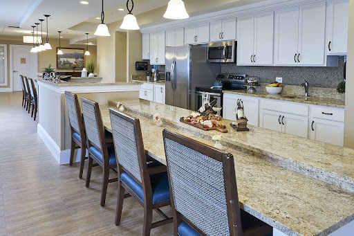 A modern kitchen featuring a granite countertop with bar stools and contemporary appliances.