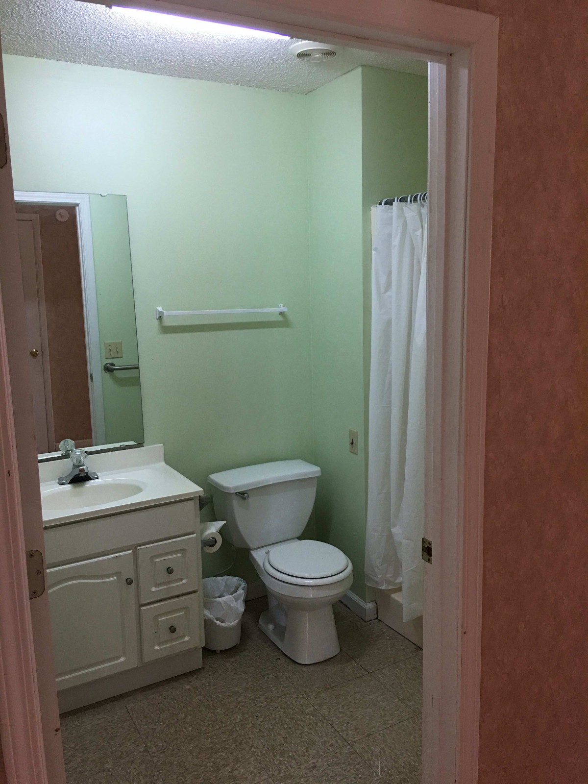 A small bathroom with a toilet, sink, and shower.