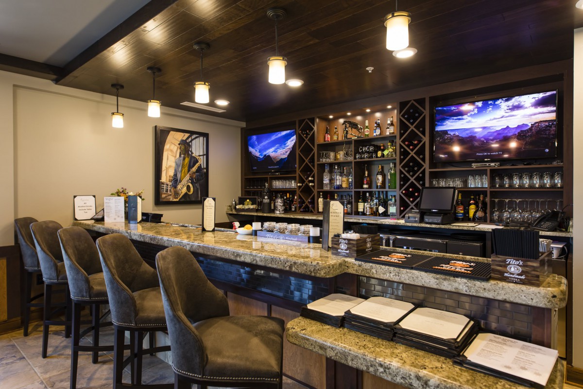 A cozy bar interior featuring a granite countertop, plush seating, and a well-stocked wine rack.