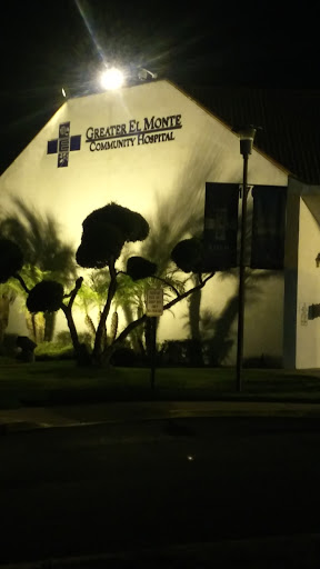 A well-lit community hospital at night, surrounded by illuminated trees.