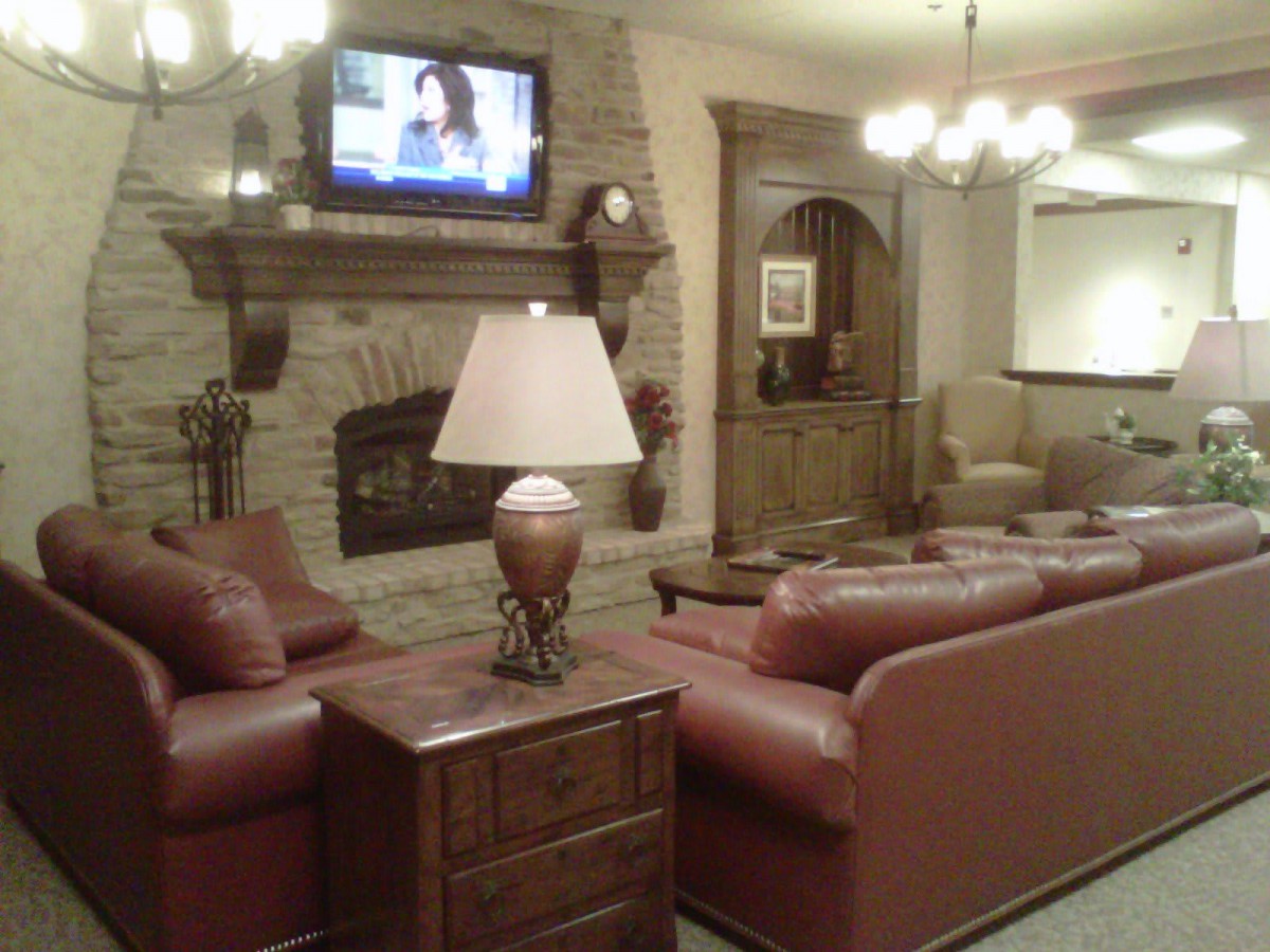 A cozy living room with leather sofas, a fireplace, and a television mounted above.
