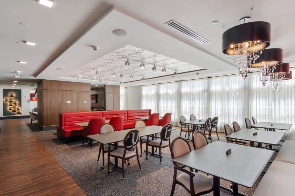 A modern restaurant interior featuring tables, chairs, and booth seating with large windows.