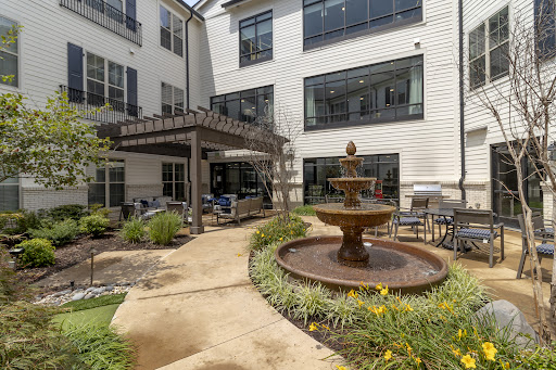 A tranquil courtyard featuring a central fountain and comfortable outdoor seating, surrounded by modern residential buildings.