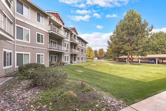 A residential apartment building with well-maintained grass and trees.