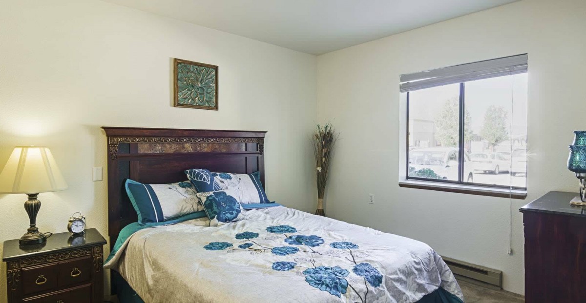A cozy bedroom with floral bedding and a window letting in natural light.
