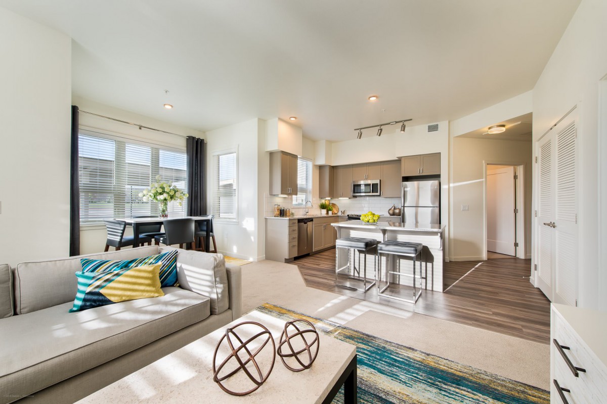 A modern open floor plan featuring a bright living room and kitchen area.