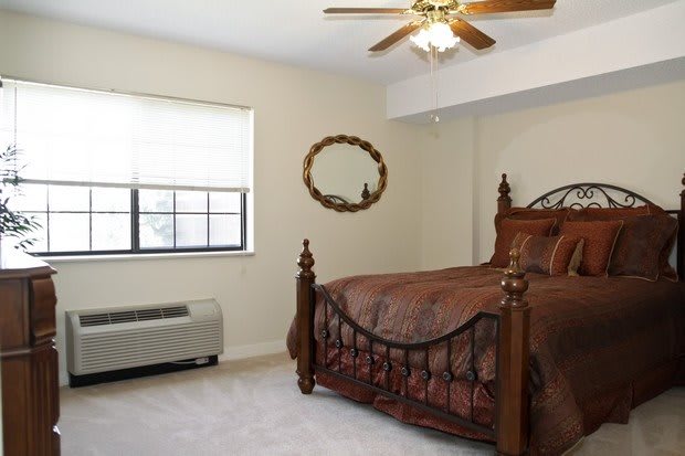 A cozy bedroom featuring a wooden bed and a ceiling fan.