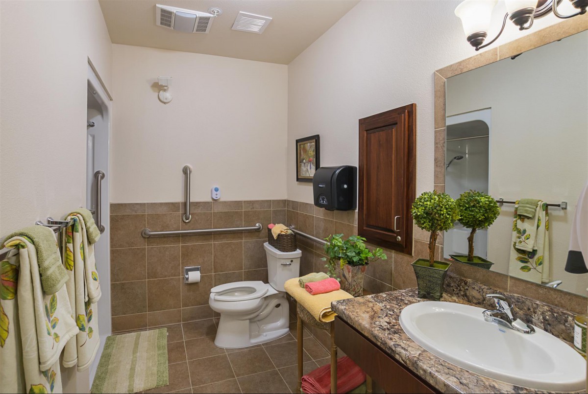 A well-decorated bathroom with a toilet, sink, and decorative plants.