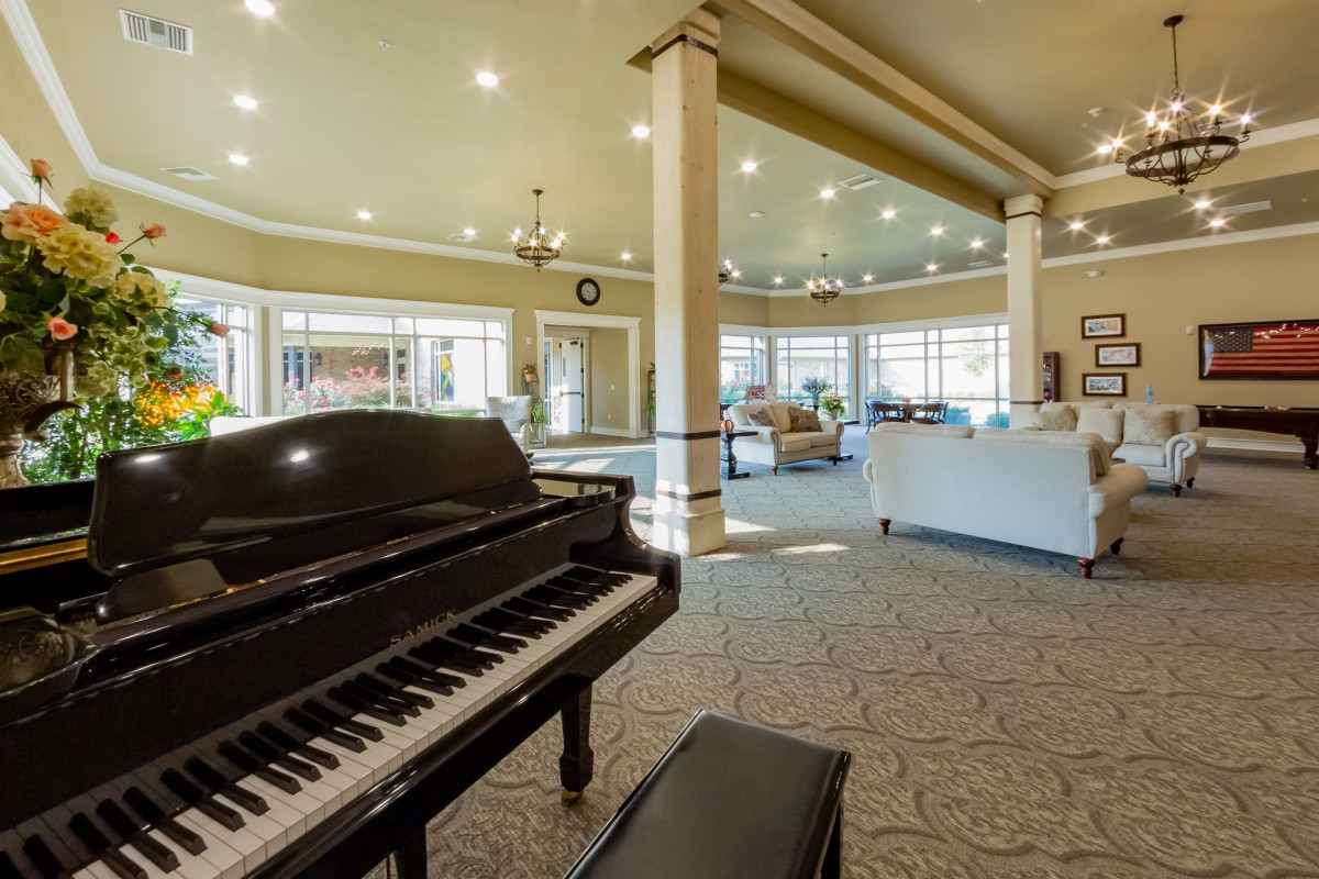 A spacious lobby interior featuring a grand piano and comfortable seating with abundant natural light.