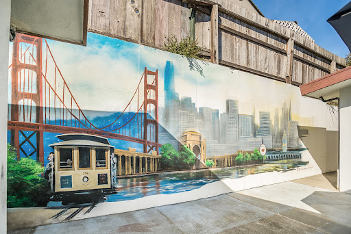 A vibrant mural depicting the Golden Gate Bridge and a classic San Francisco cable car, showcasing the city's iconic skyline.