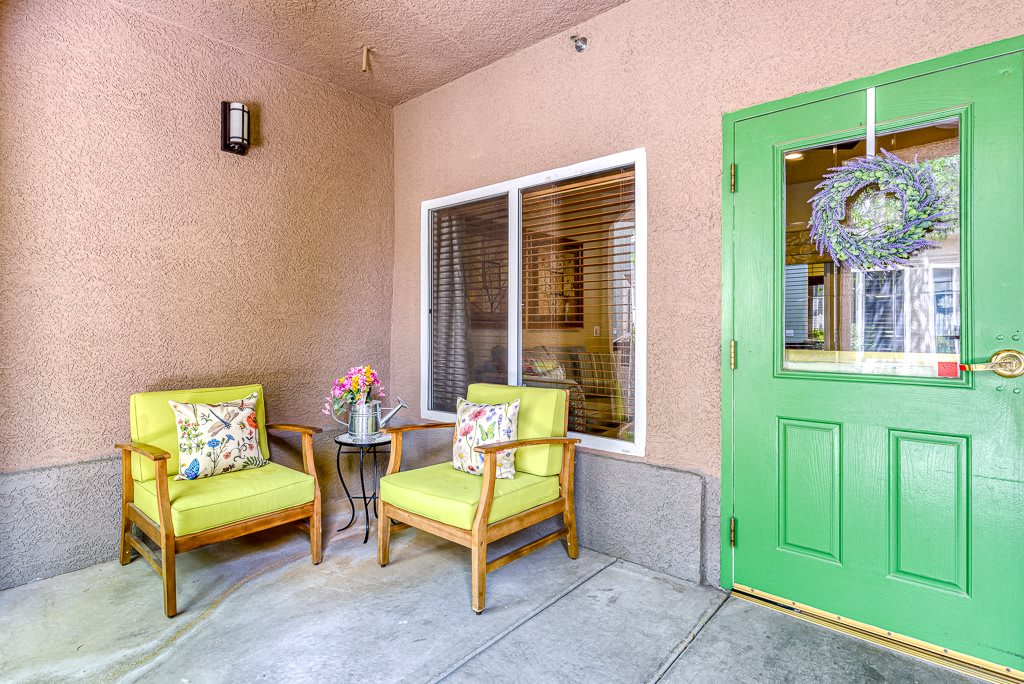 A cozy patio with two cushioned chairs and a bright green door.